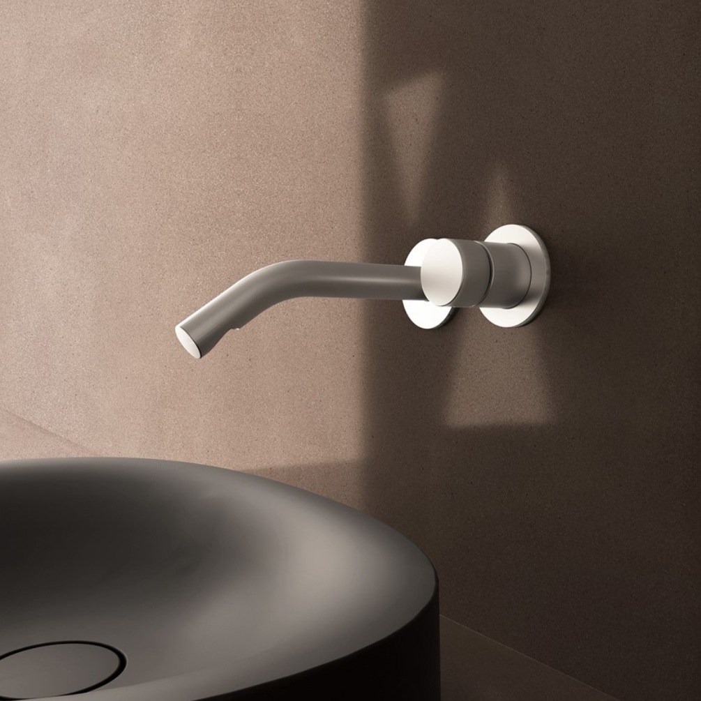 Lifestyle image of the Crosswater Ixora Stainless Steel Wall Mounted Basin Mixer installed behind a black countertop basin